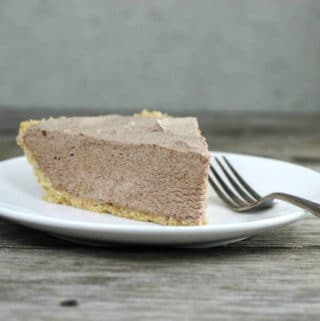 Chocolate pie with a fork on the side on a white plate.