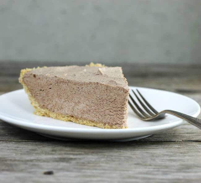 Chocolate pie with a fork on the side on a white plate.