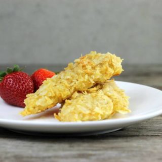 Chicken tenders with strawberries on a white plate.