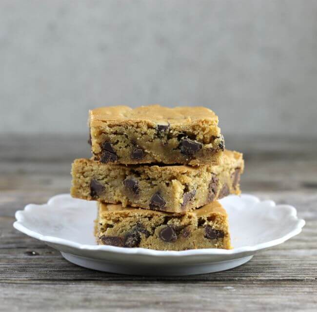 Side view of three chocolate chip bars on a round white plate.