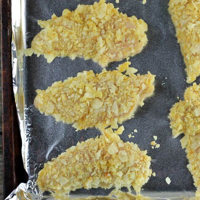 Unbaked chicken tenders on a baking pan.