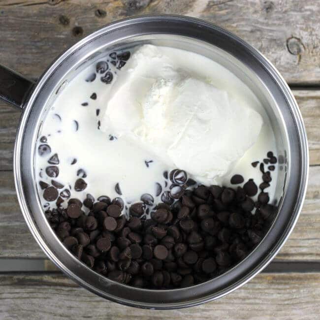 Chocolate chips, cream cheese, and cream in a saucepan.