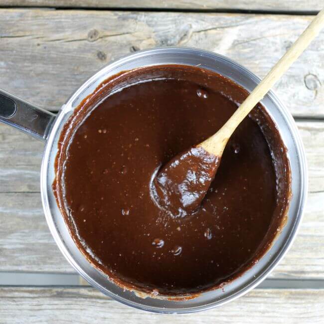 Melted chocolate in a sauce pan with a wooden spoon in the pan.