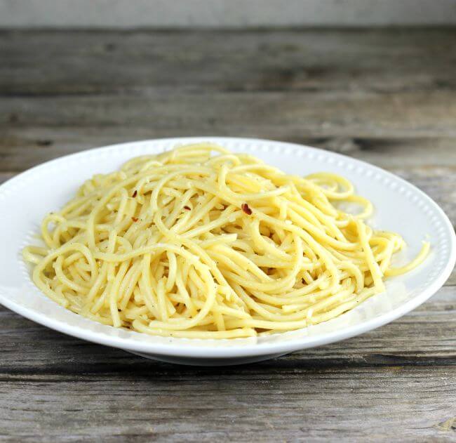 Side angle view of spaghetti noodles on a white plate.