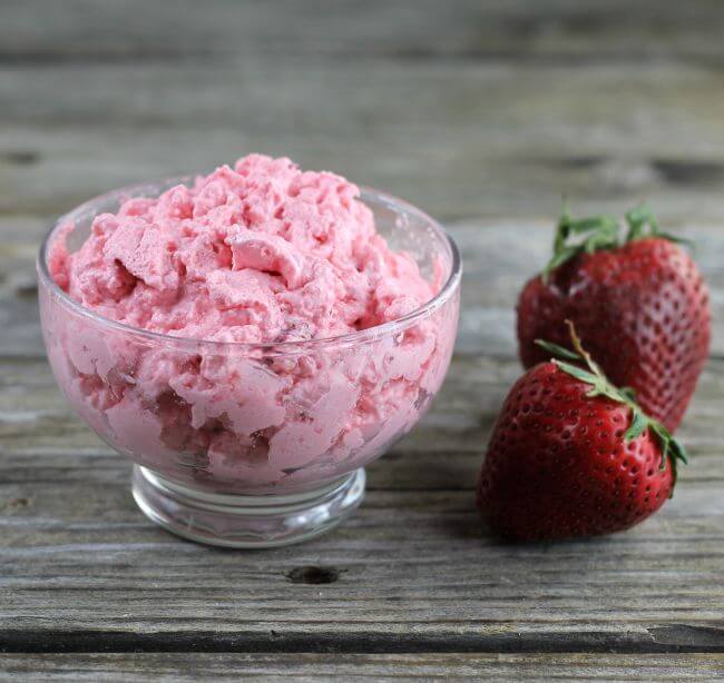 Jello in a bowl with two strawberries on the side.