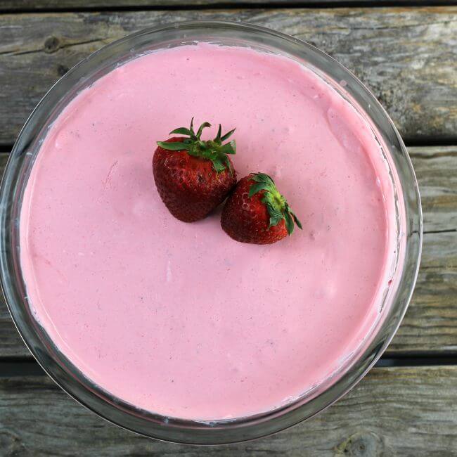 Strawberries are on top of a jello strawberry salad.