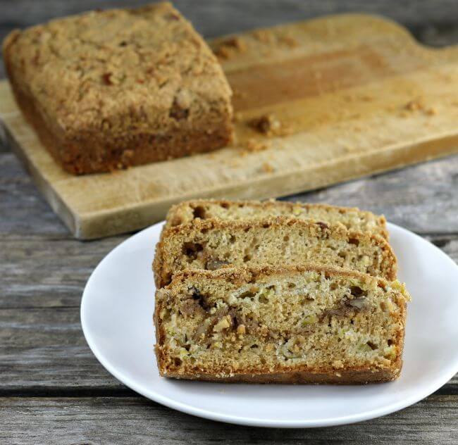 A plate of sliced quick bread with a loaf of bread behind the plate.