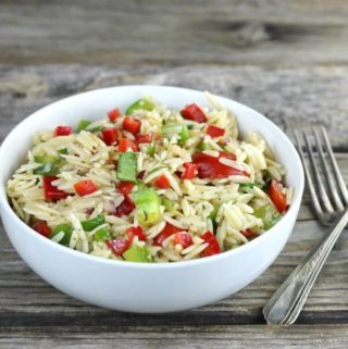 Side angle view of orzo pasta salad in a white bowl.