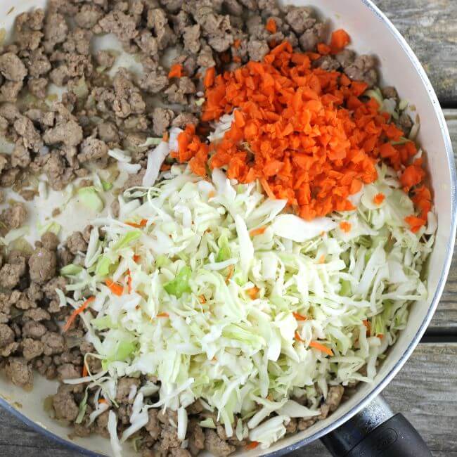 Cabbage and carrots are added to the ground pork.