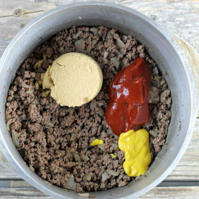 Fried hamburger, brown sugar, ketchup, and mustard in a Dutch oven.