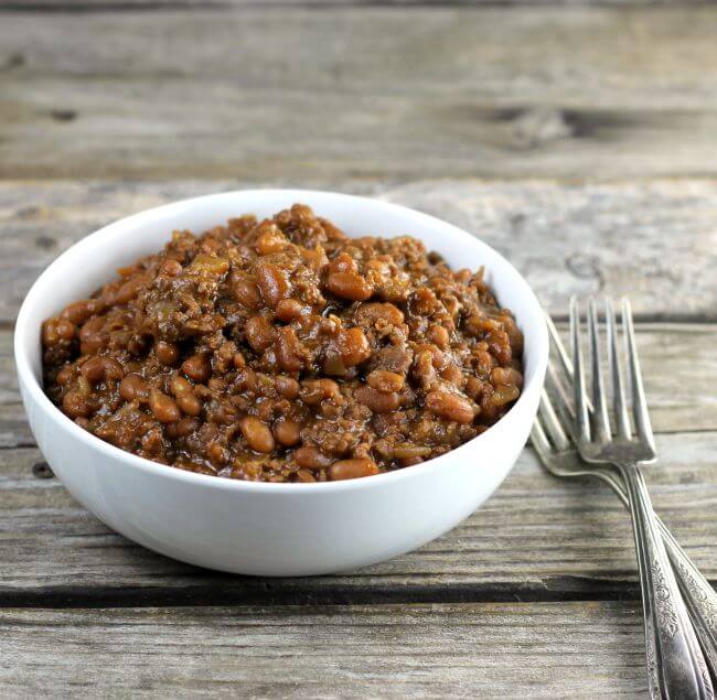 Side angle view of a bowl of beans with two forks on the side.