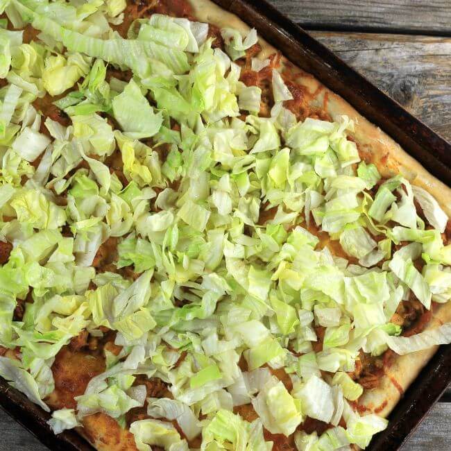 Lettuce is added to the top of the baked pizza.
