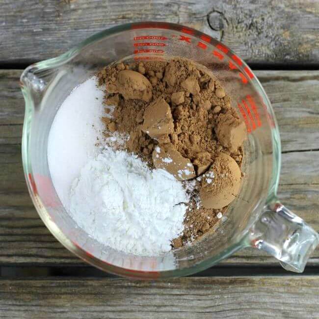 Cocoa, sugar, and corn starch added to a measuring cup.