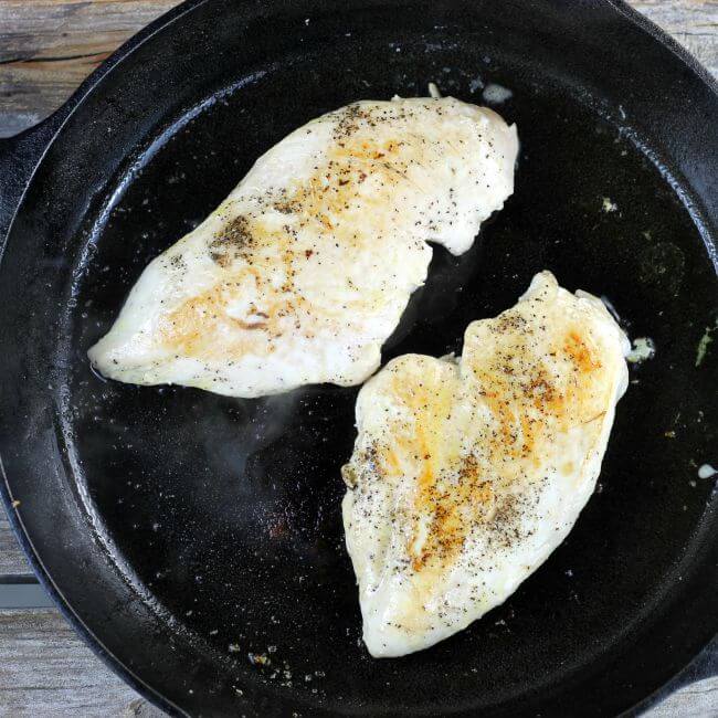Two chicken breast in a cast-iron skillet.