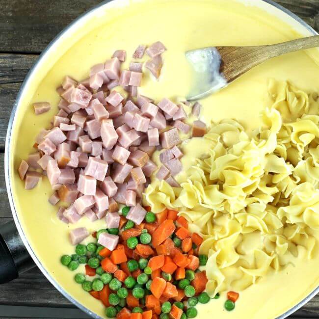 Noodles, ham, peas, and carrots added to the cheese sauce.