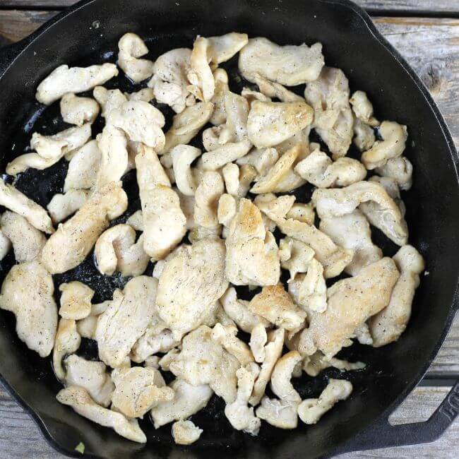 Sauted chicken slices in a skillet.