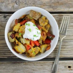 Loaded potato skillet in a bowl topped with sour cream and green onions.