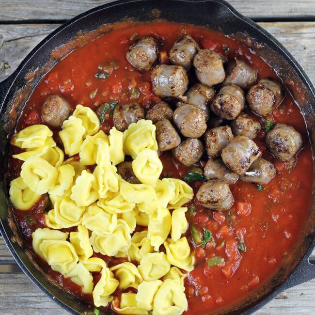 Tortellini and sausage is added to the tomatoe sauce.