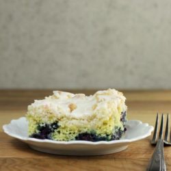 Side view of lemon blueberry coffee cake on a white plate.