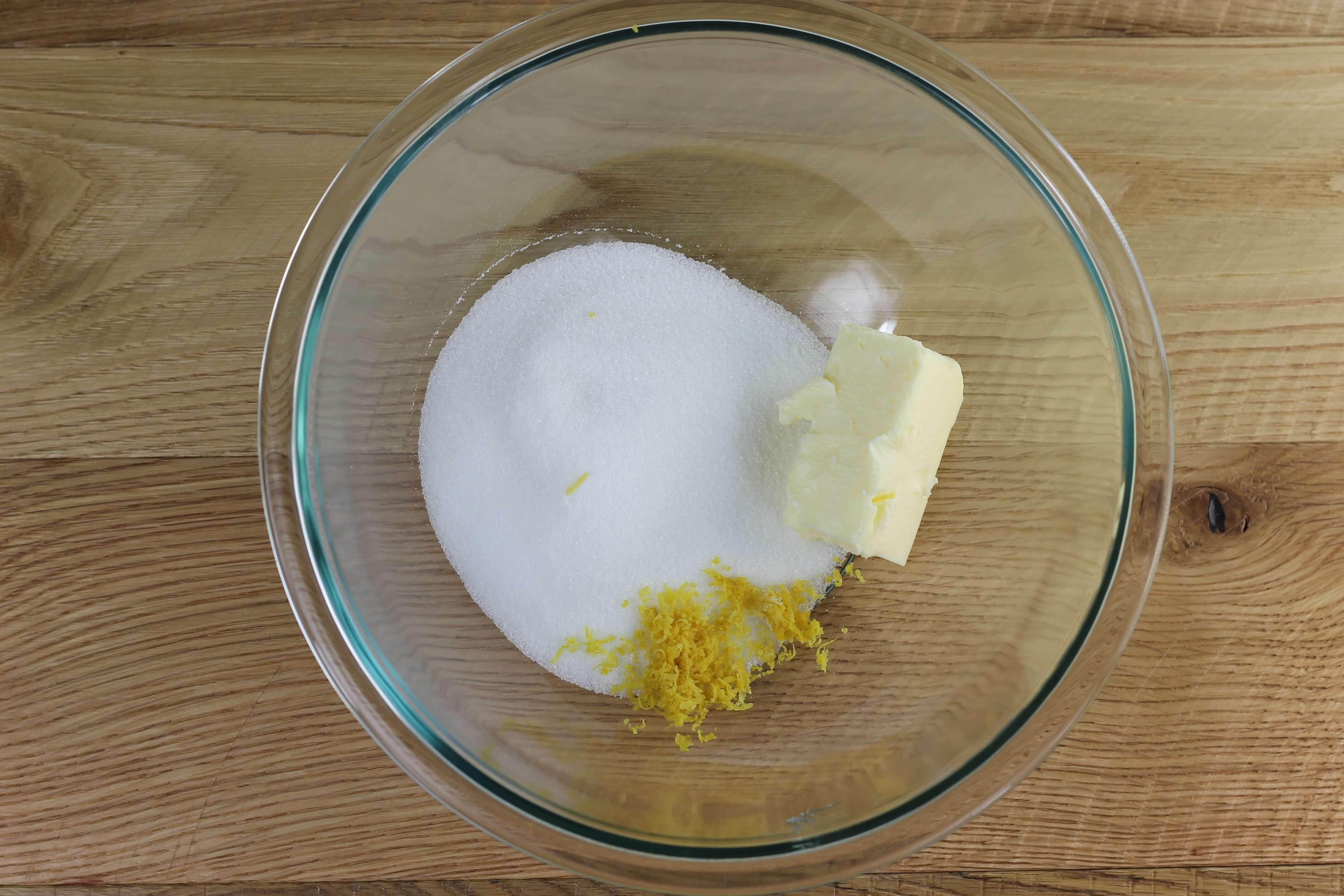 Sugar, butter, and lemon zest in a glass bowl.