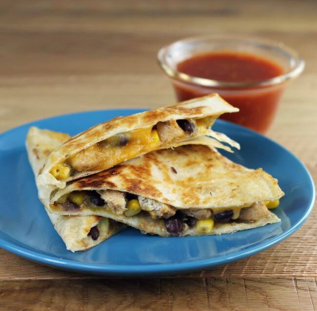 A side view of quesadilla on a plate with salsa in the background.