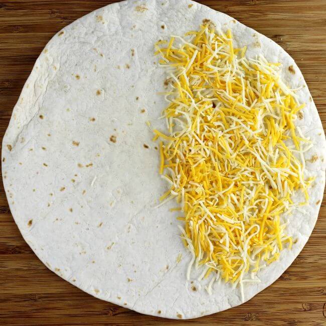Cheese is sprinkle over half of the tortilla shell.