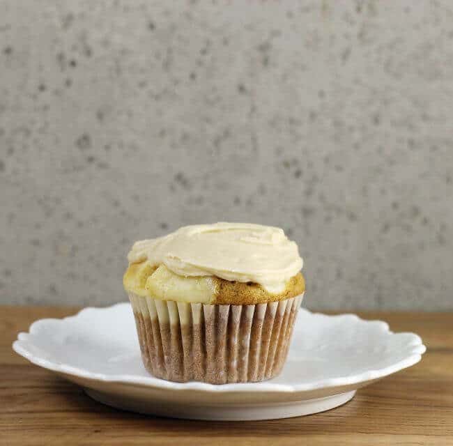 A pumpkin cream cheese cupcake sitting on a white plate.