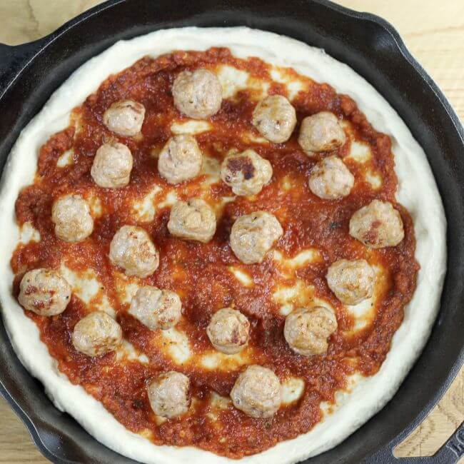 The cooked meatballs are added to the pizza.
