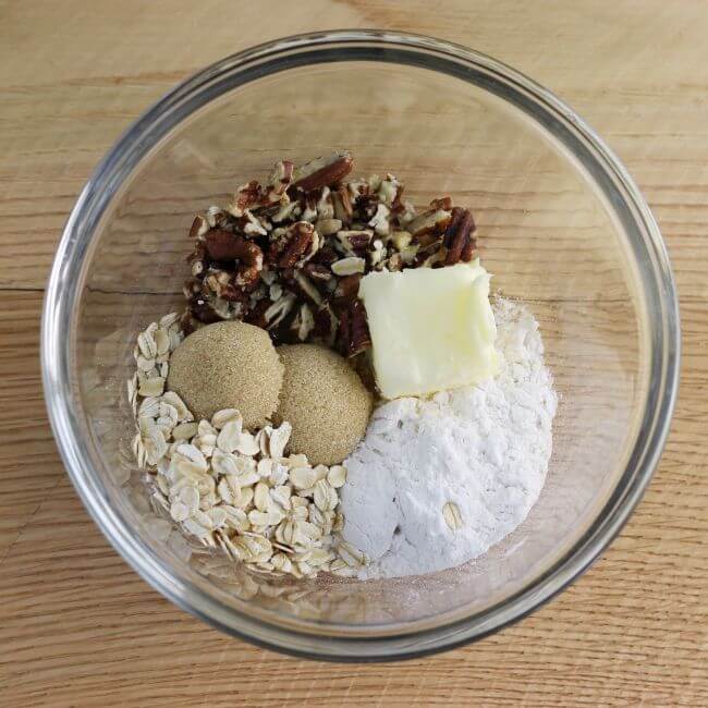 Flour, brown sugar, flour, oats, and butter in a bowl.