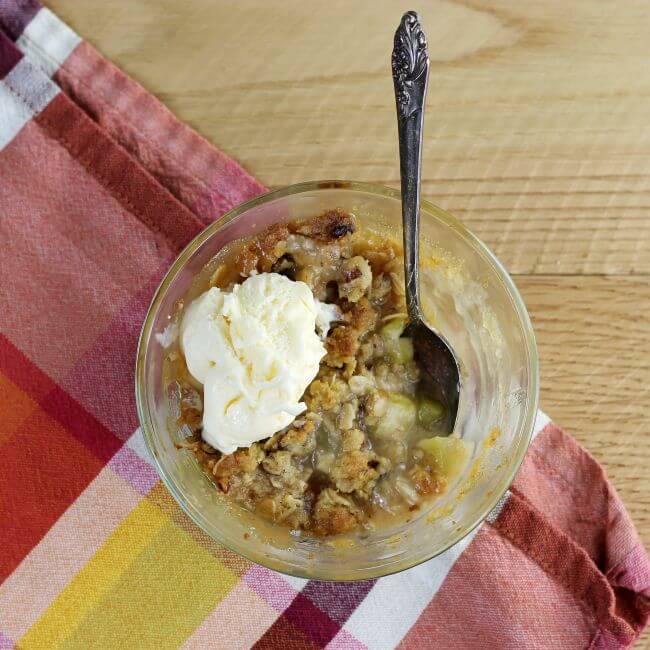 Looking down at a bowl of crisp with a scoop of ice cream and a spoon in the bowl.