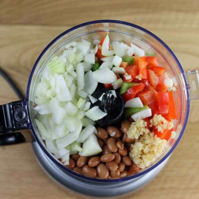 Vegetables are added to a food processor. 