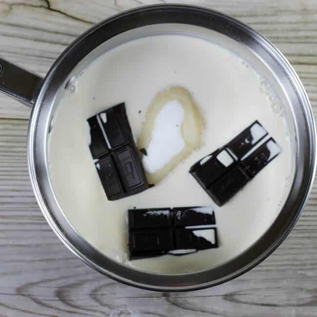 Looking down at a saucepan with chocolate squares, sugar, and milk.