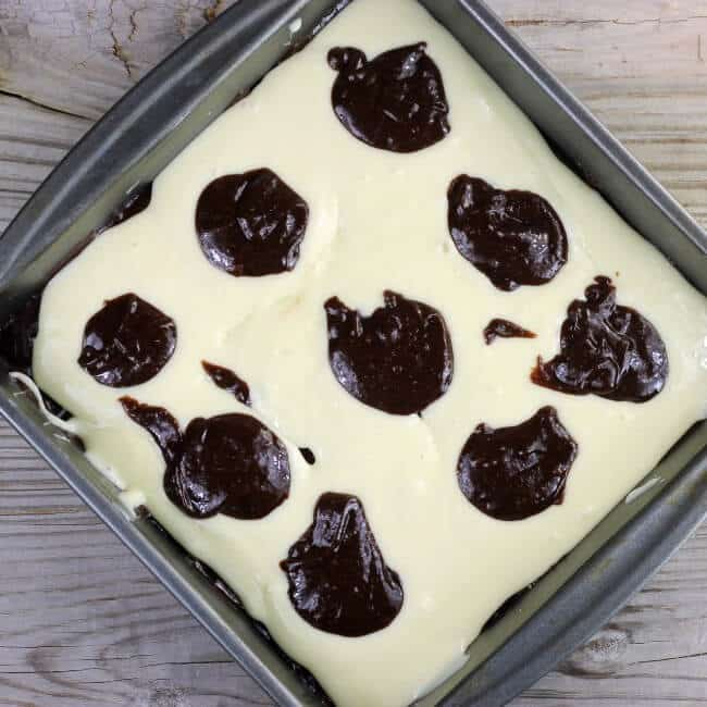 Spoonful of brownie batter is dropped over top o the cream cheese filling.