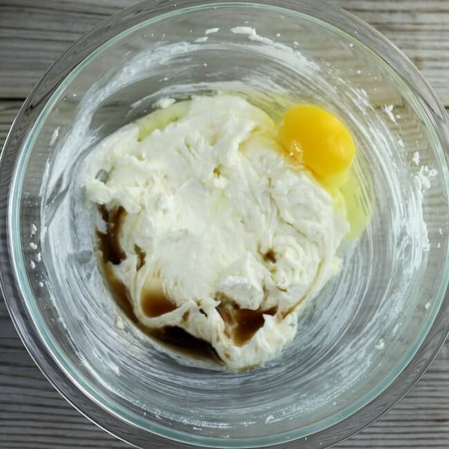 Vanilla and a egg are added to the bowl with the cream cheese mixture.