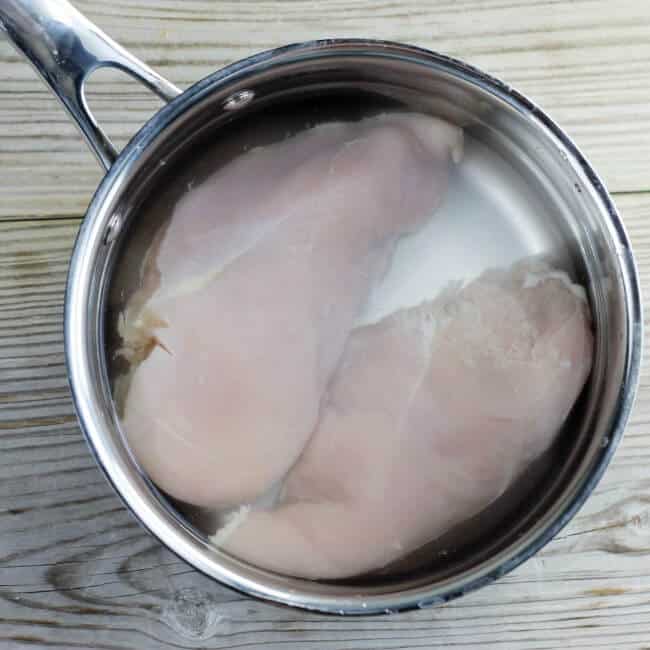 Raw chicken and water in a large saucepan.