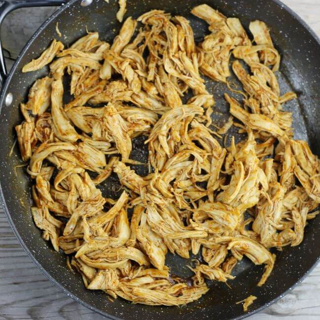 Taco flavored shredded chicken in a skillet.