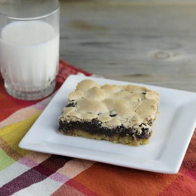 Looking at a side view of a bar on a square plate with a glass of milk on the side.