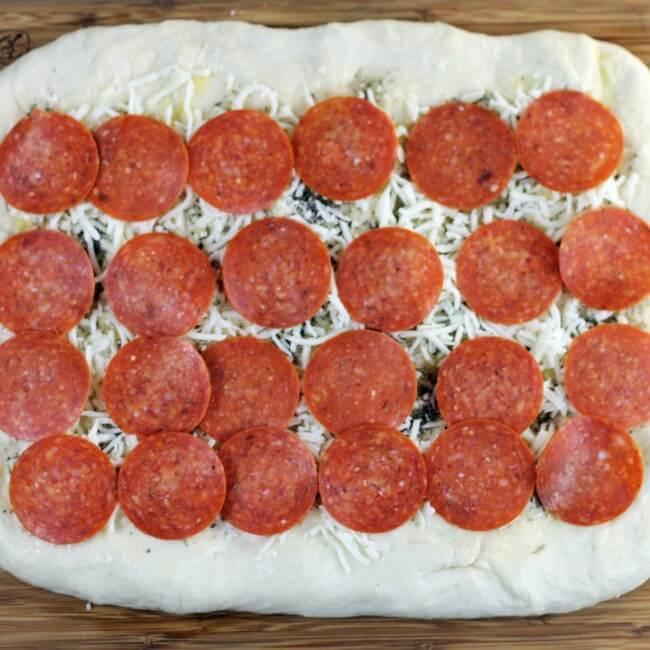 Pepperoni is placed on top of the cheese.