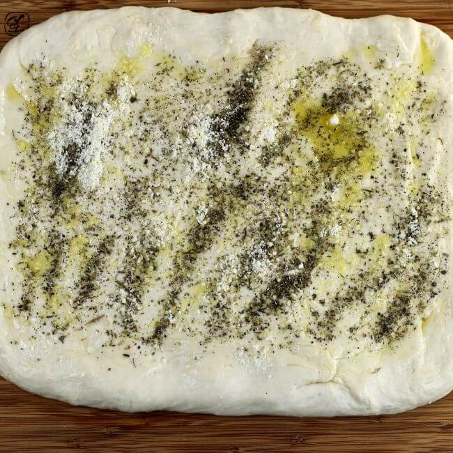 Seasoning and parmesan cheese is added to the top of the dough.