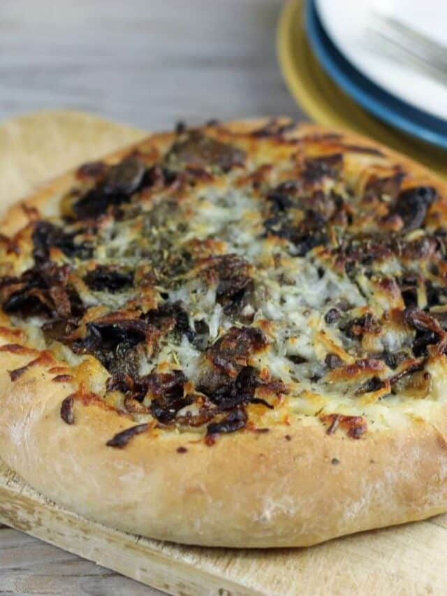 A side view of a caramelized onion and mushroom pizza.