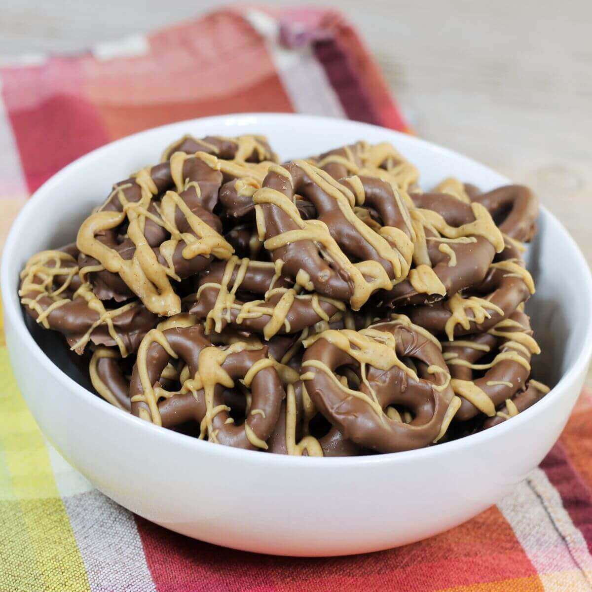 A bowl of pretzels covered with chocolate and peanut butter.