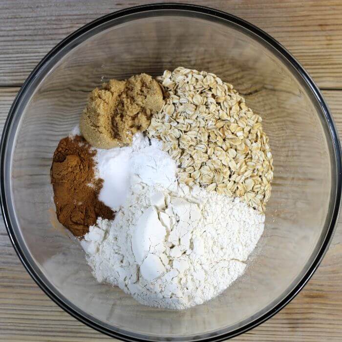 Flour, oats, brown sugar, sugar, cinnamon, and baking powder are added to a large bowl.