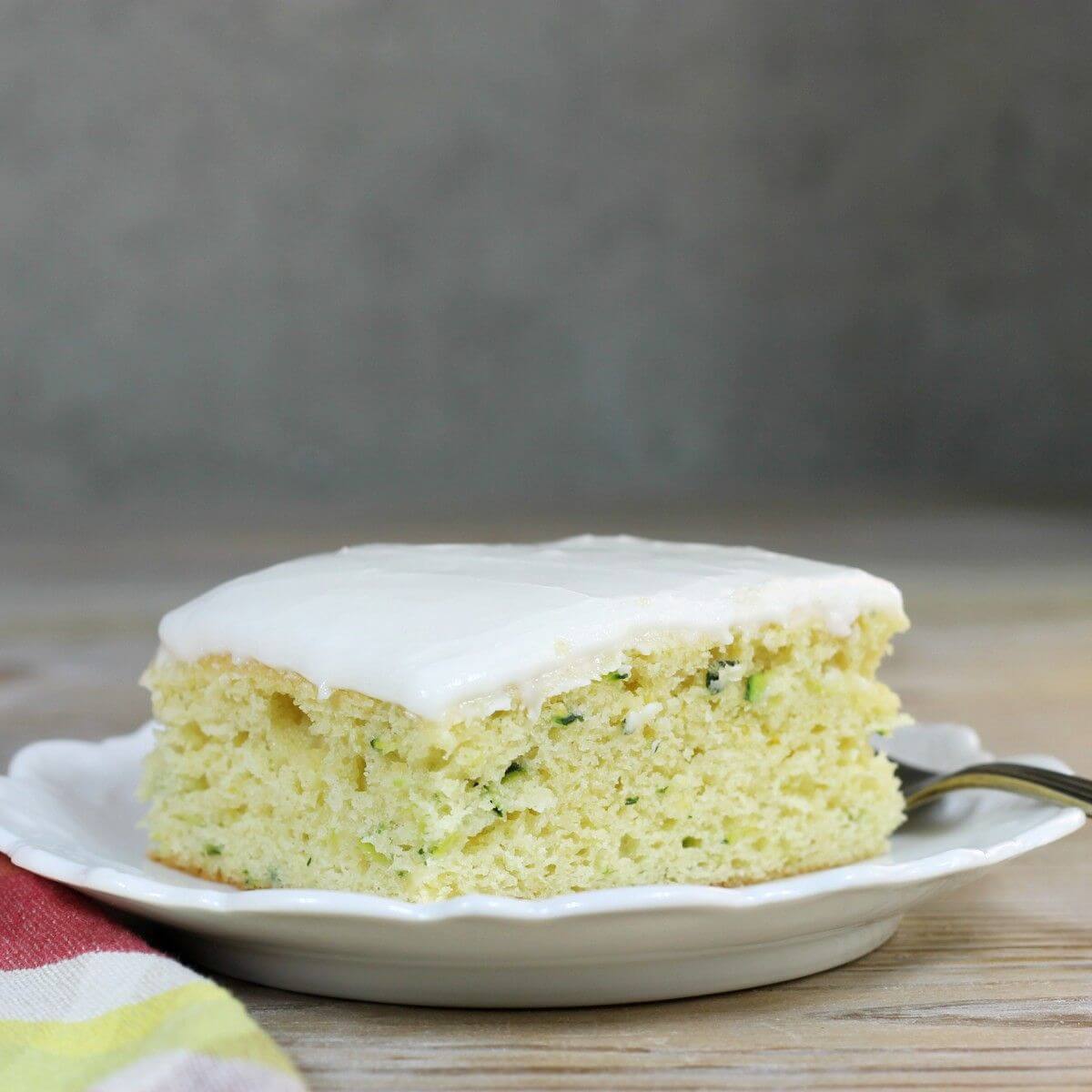 A side view of a piece of cake on a white plate. 
