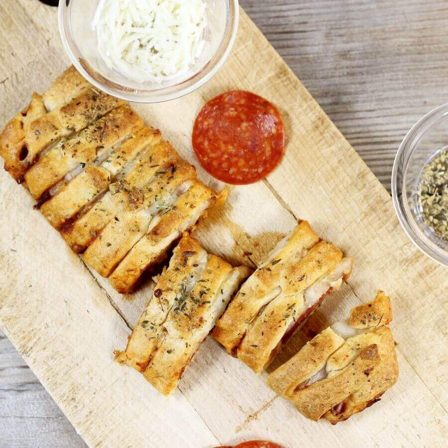 Overlooking a crescent roll pizza braid on a wooden cutting board.