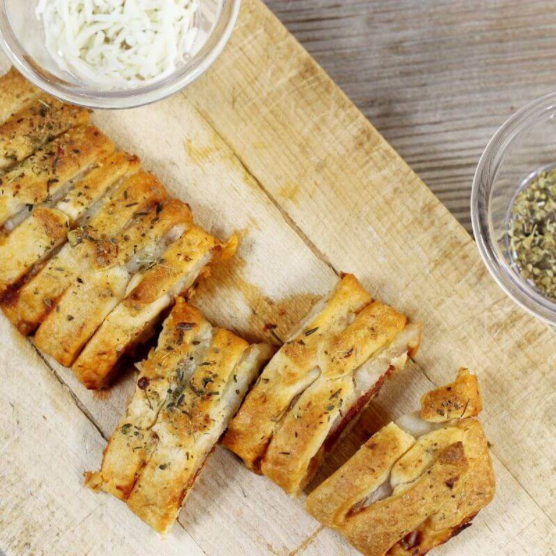 Looking down at a wooden cutting board with a pizza braid on it.