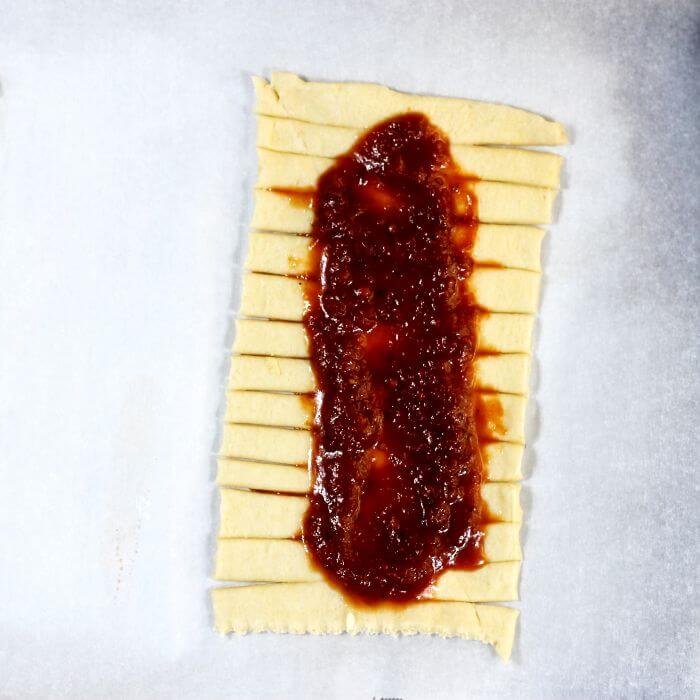 Pizza sauce is put down the middle of the crescent roll.