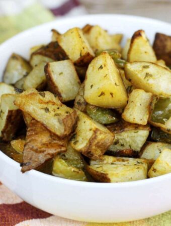 a side view closeup of a white bowl of roasted potatoes.