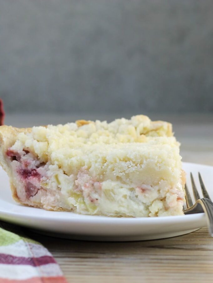 Side view of a slice of rhubarb pie on a white plate.